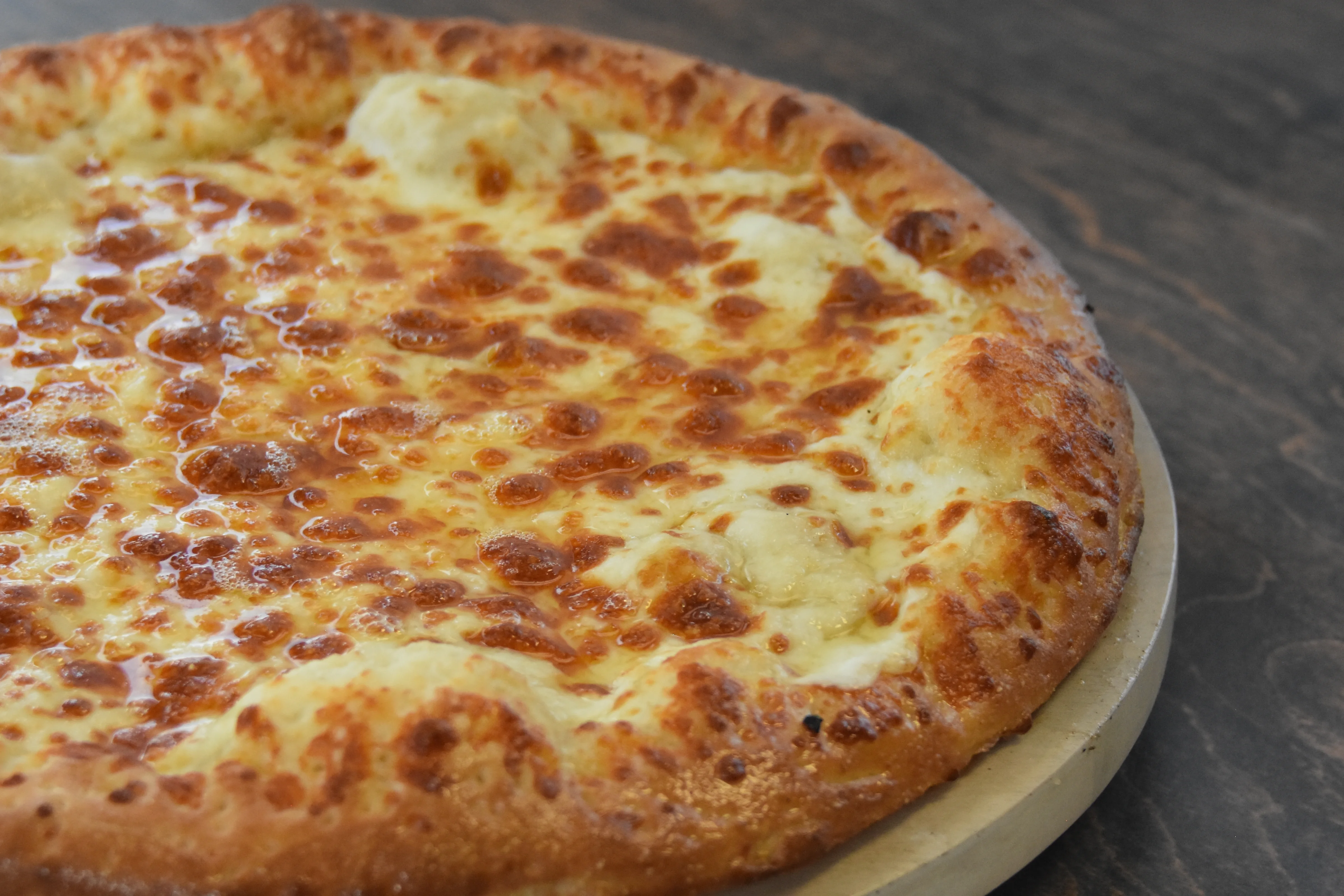 Freshly baked cheese pizza on a wooden table.
