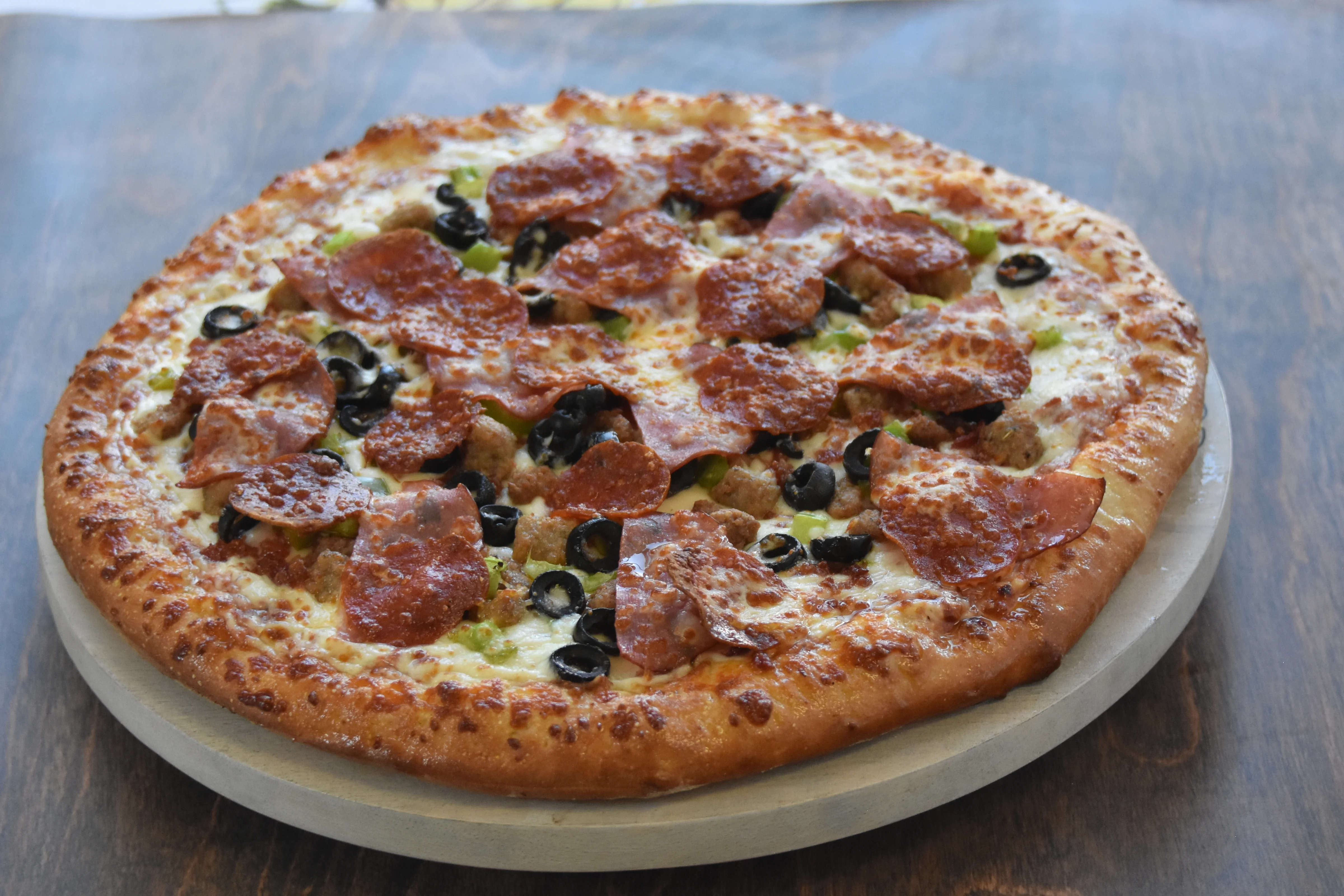 Delicious pepperoni and olive pizza on a wooden table.