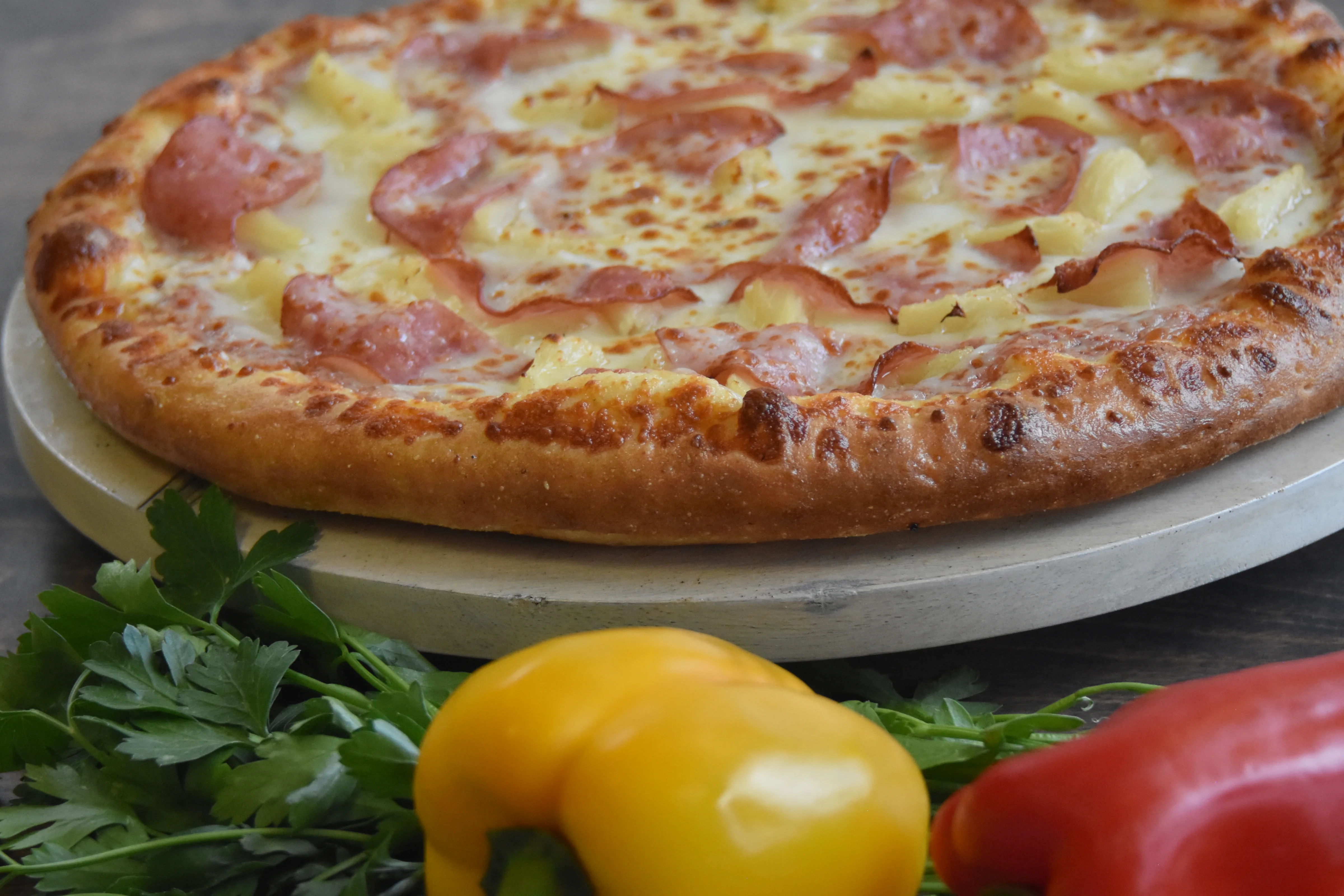 Delicious pizza with ham and pineapple on a wooden surface