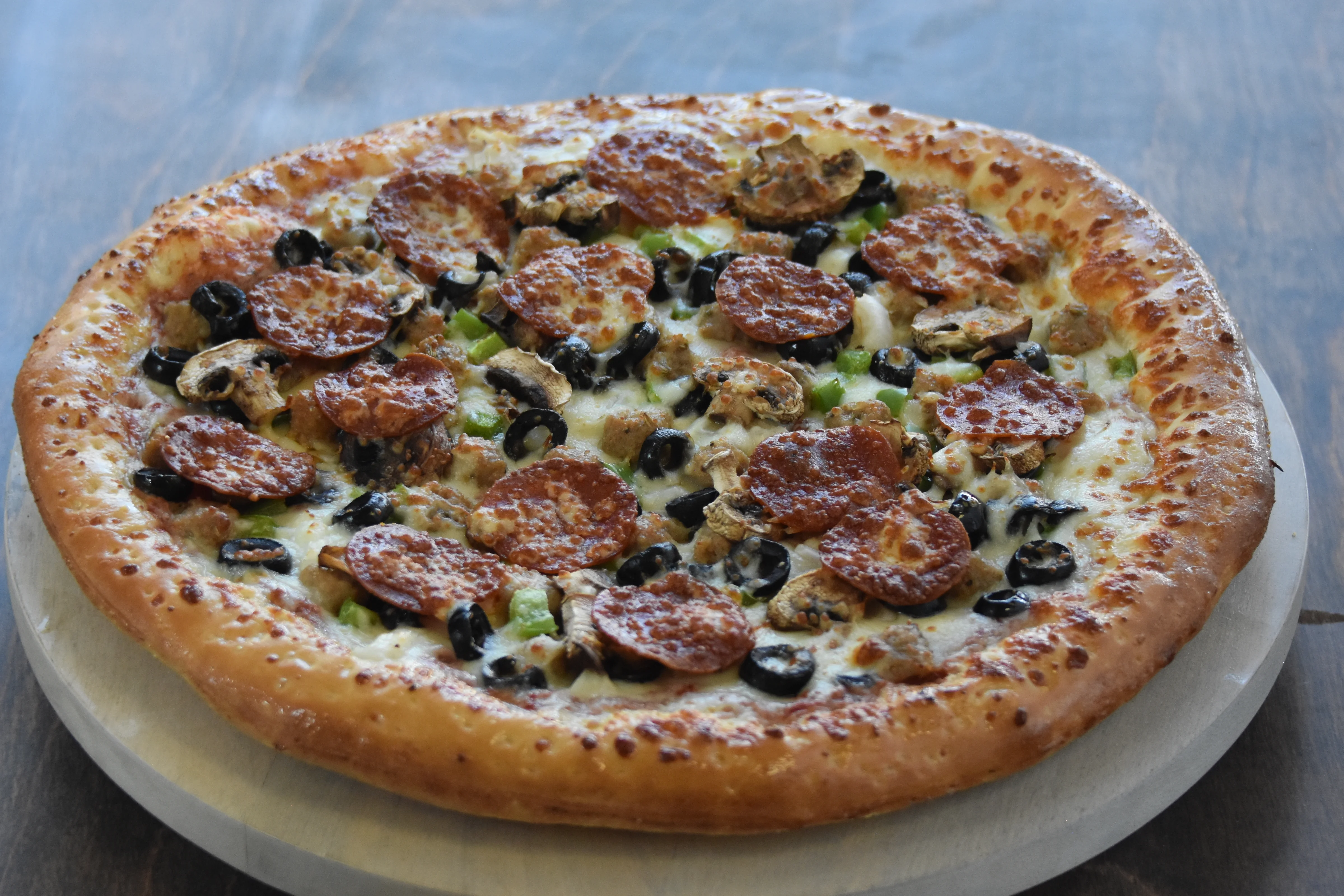 Delicious pepperoni and mushroom pizza on wooden board.