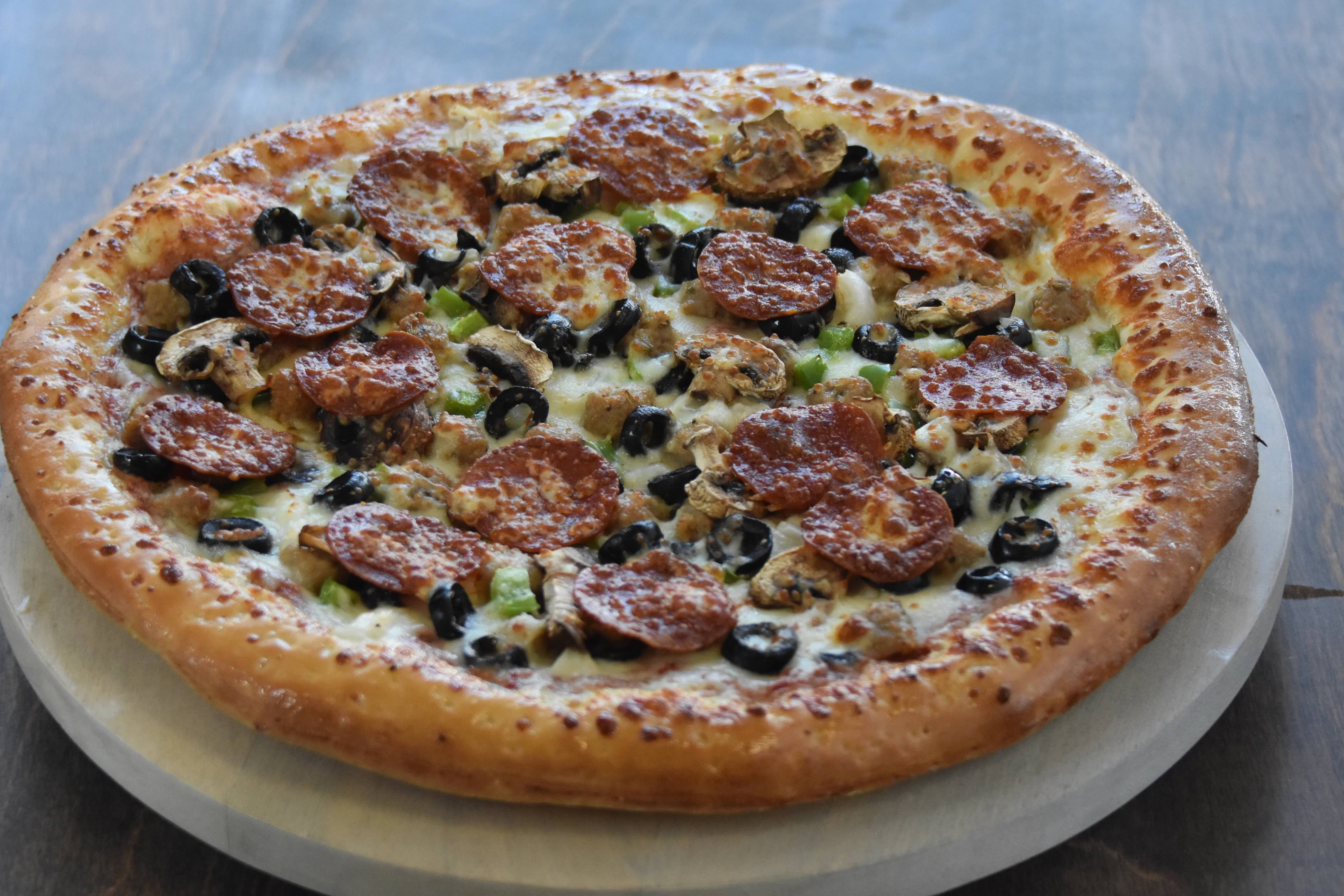 A delicious pizza topped with pepperoni, olives, and green peppers.